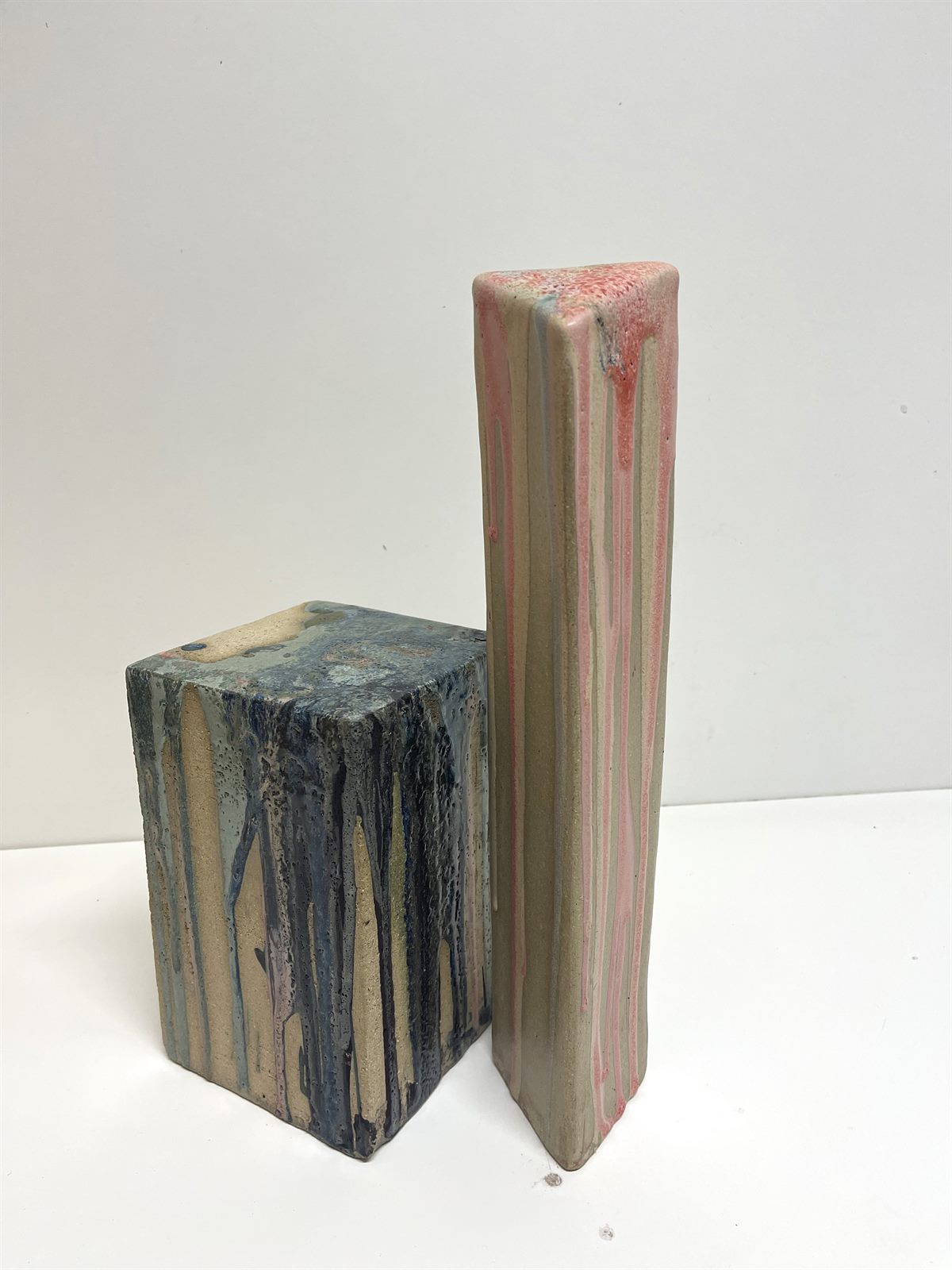 Contrast — two hand-built raku slab columns, one glazed in blues, the taller one in pink and coral, glaze running down the sides