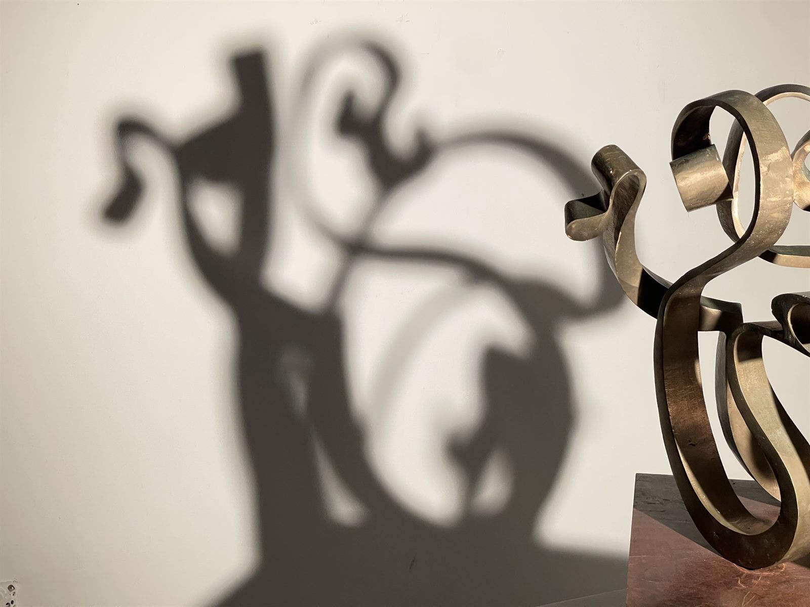 LOVE / Shadow — bronze sculpture and its projected shadow on the wall
