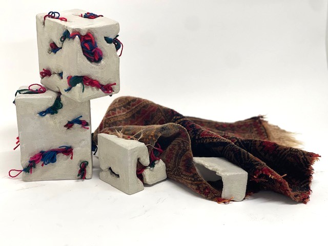 Threads of Home — clay forms resting on and beside the spread Persian rug