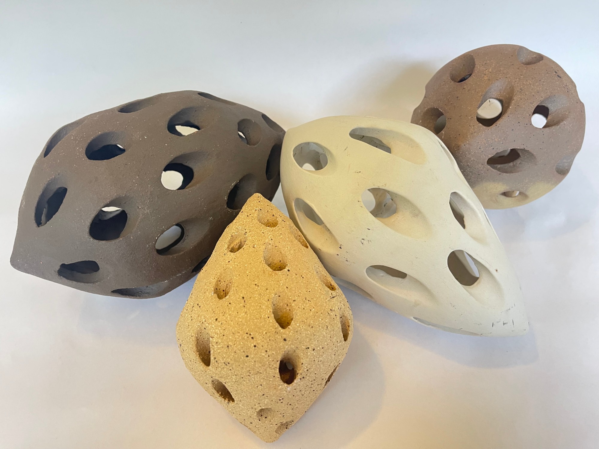 The Touch of Memory — four pierced Raku forms in dark brown, cream, buff and speckled clay, grouped together