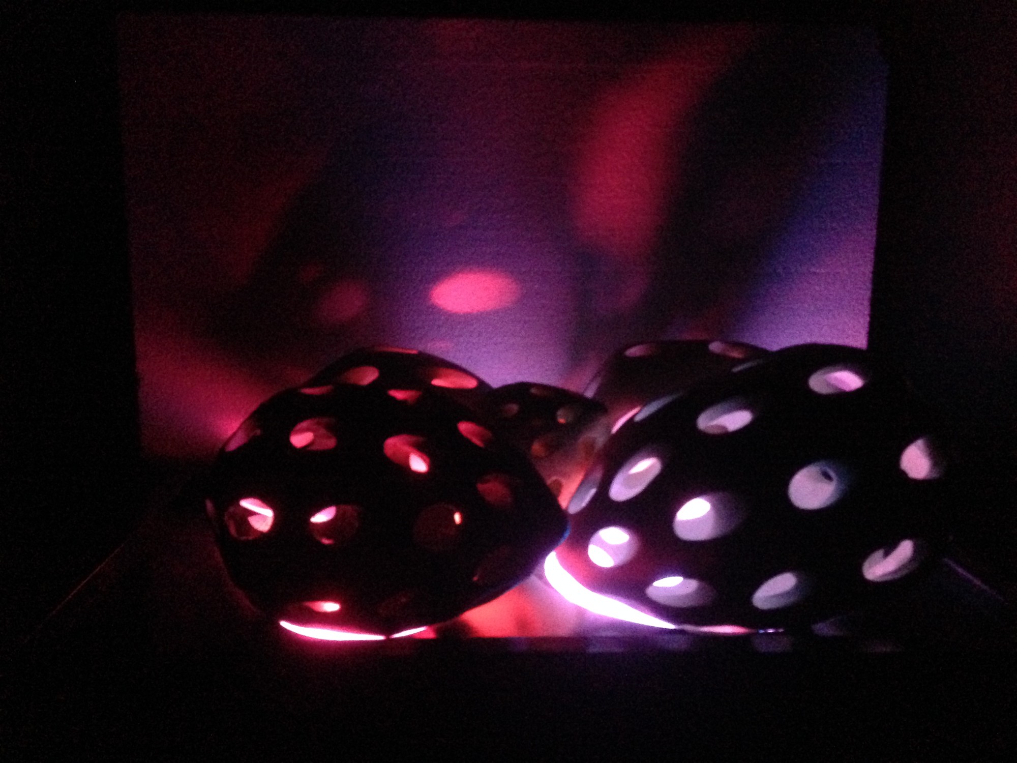 The Touch of Memory — pierced ceramic forms glowing red and violet, light spilling through the openings